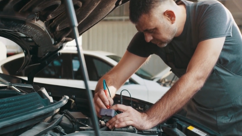 A Mechanic Troubleshooting Electrical Problems Under the Hood of A Car in A Repair Shop